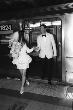 a man and woman in formal wear exiting a subway train with bouquets of flowers