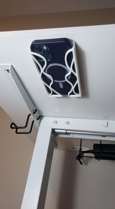 a cell phone mounted to the ceiling in a room with white walls and metal brackets