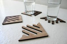 four wooden coasters sitting on top of a white counter next to two water glasses