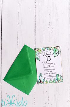 a green envelope with a wedding card on it next to an envelope that has the number thirteen printed on it