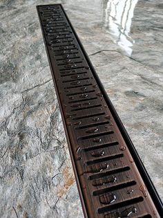 a long metal grate sitting on top of a stone floor