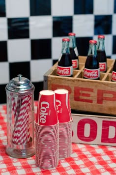 coca - cola cans are lined up on a checkered tablecloth