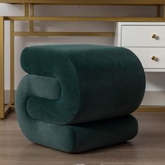 a green chair sitting on top of a wooden floor next to a white dresser and desk