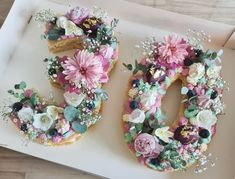 the letter o is decorated with flowers and greenery on top of an open box