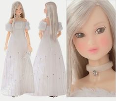 the doll is wearing a white dress with pearls on it's neck and long blonde hair