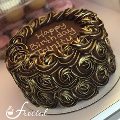 a chocolate birthday cake with the words happy birthday written in gold frosting on it