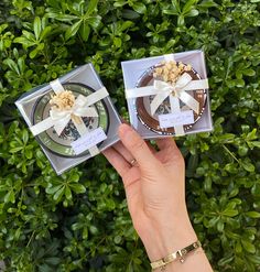 someone holding two small boxes with food in them on top of some bushes and trees