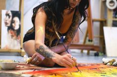 a woman sitting on the floor painting with her hands