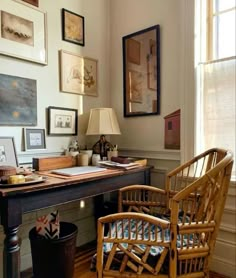 a desk with two chairs and pictures on the wall above it in a home office