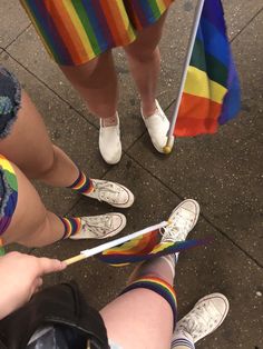 two people standing next to each other with colorful socks on and one holding a rainbow flag