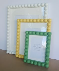 two white and yellow frames sitting next to each other on top of a wooden table