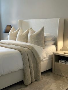 a bed with white linens and pillows in a bedroom next to a night stand