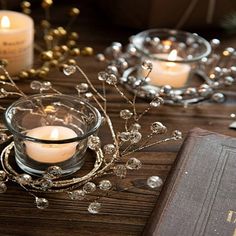 some candles are sitting on a table next to an old book and glass candle holders