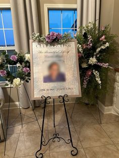 a sign in front of two windows with flowers on it and a memorial plaque next to the window