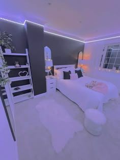 a white bed sitting in a bedroom next to a tall window with lights on it