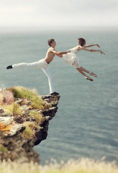 two people are doing yoga on the edge of a cliff