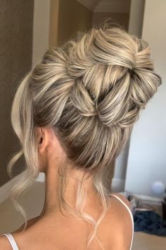 a woman with blonde hair in a messy updo is looking at the camera and has her back to the camera