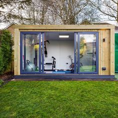 an outdoor gym with sliding glass doors and exercise equipment in the back yard, surrounded by green grass