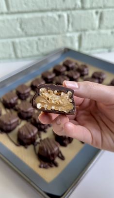 a hand holding up a chocolate bar with walnuts on it