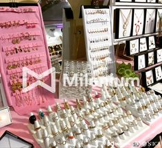 many different types of earrings on display at a market stall with pink table cloth and white trays filled with jewelry