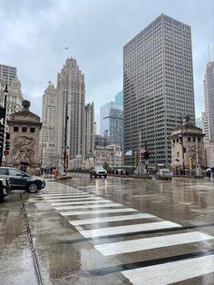 an intersection in the middle of a city with cars driving on it and tall buildings