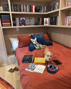 a small dog sitting on top of a bed next to a book shelf filled with books