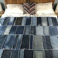 a bed made up with blue jeans and pillows on top of the bedspread