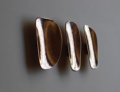 three silver spoons sitting next to each other on a gray surface with white background