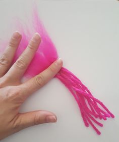 a person's hand is shown with pink yarn