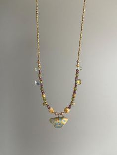 a necklace with beads and charms hanging from it's sides on a chain that is attached to a wall