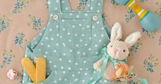 a stuffed rabbit sitting next to a blue polka dot overalls