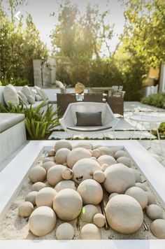 an outdoor living area with white furniture and large rocks on the ground in front of it