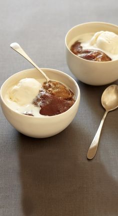 two bowls filled with pudding and ice cream next to spoons on top of a table