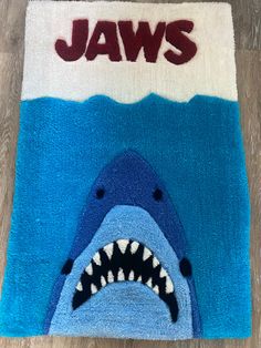 a blue rug with a shark on it and the word jaws written in large letters