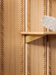 a glass vase sitting on top of a wooden shelf next to a door knobs