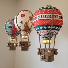 three hot air balloons with christmas decorations on them hanging from the side of a wall