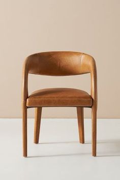 a wooden chair sitting on top of a white floor next to a wall and a light colored wall