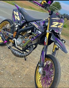 a purple and yellow dirt bike parked on the side of a road