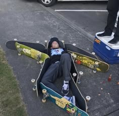 a man laying on the ground with his skateboard attached to his back and another person standing next to him