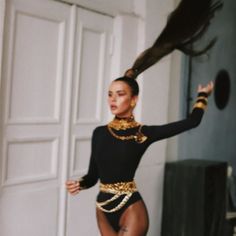 a woman in a black leotard and gold chain around her neck is dancing