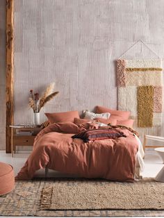 a bed with an orange comforter and pillows