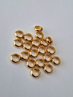 small gold plated jump rings on a white surface with spacers in the middle