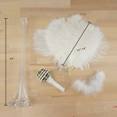 a white feather hat next to a hair dryer and measuring tape on a wooden floor