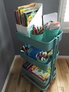 a cart filled with lots of books and pencils on top of a hard wood floor