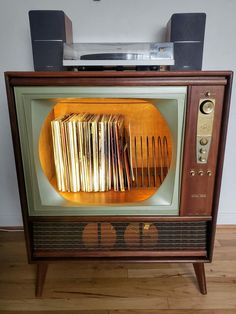 an old fashioned television set with lots of books on it's front and sides