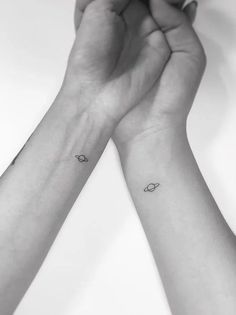 two hands holding each other with small tattoos on them