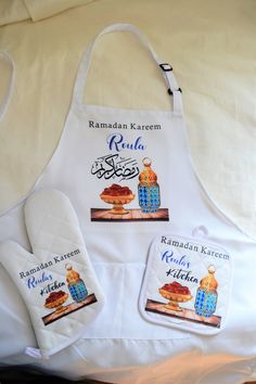 two aprons and an oven mitt are on a bed with the name raman kerem