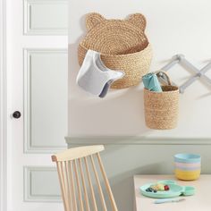 a child's room with a teddy bear toy hanging on the wall and two baskets in front of it