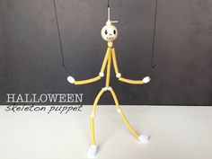 a yellow stick figure holding two strings with the words halloween written on it and an image of a skeleton hanging from one string