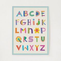 a colorful alphabet is displayed on a white wall in front of a blue framed photograph